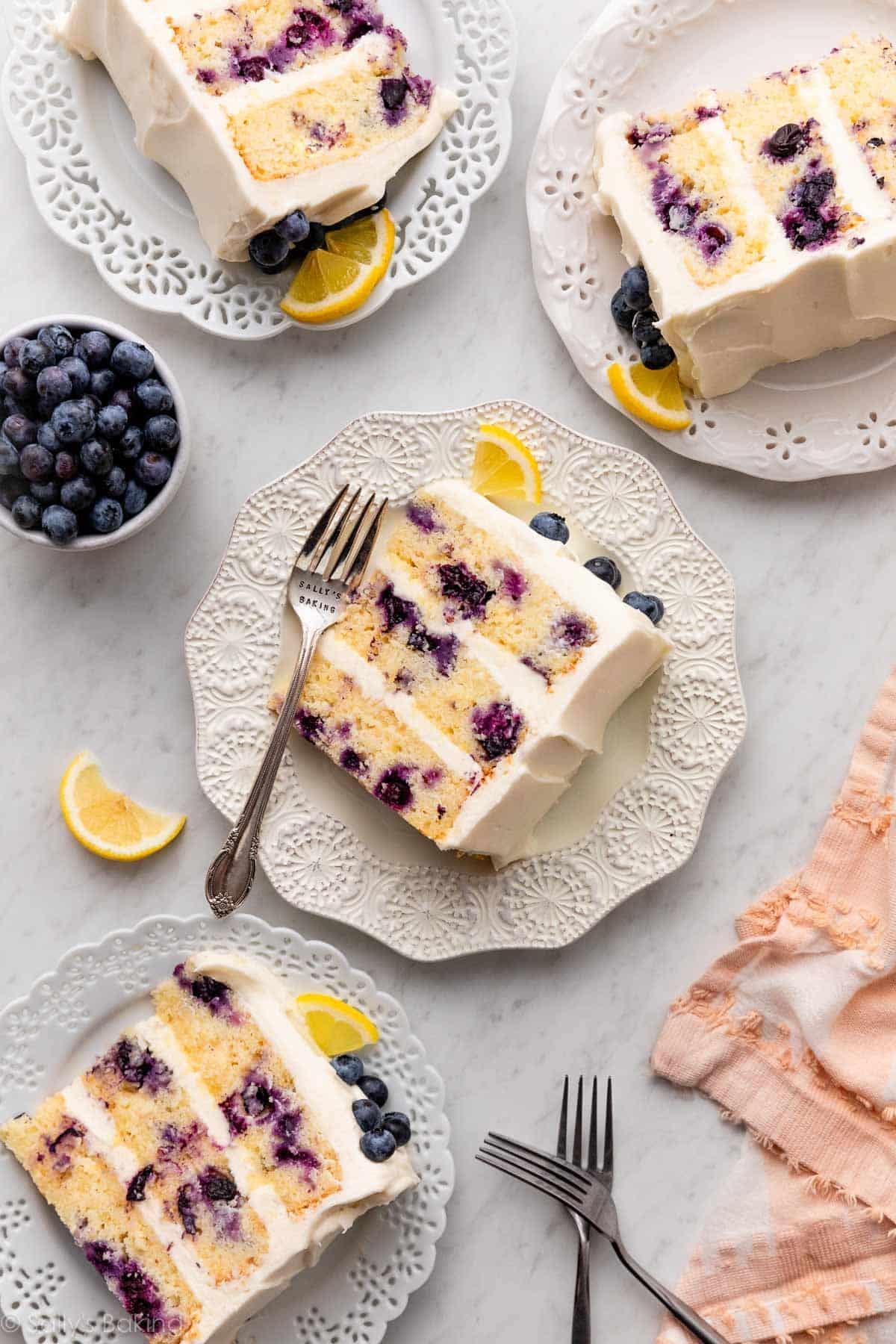 slices of lemon blueberry cake on white plates with pink linen.